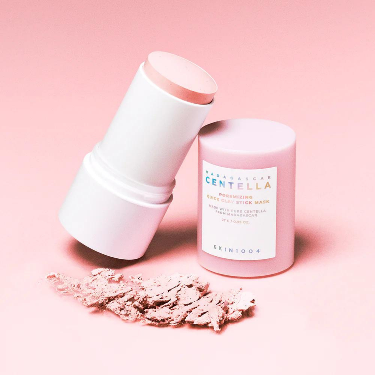 Stick de masque rose ouvert près de poudre rose et de son capuchon