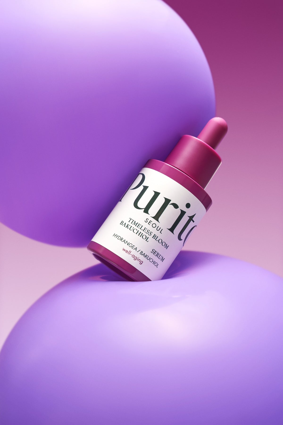 Flacon de sérum à pipette rose entre des sphères violettes