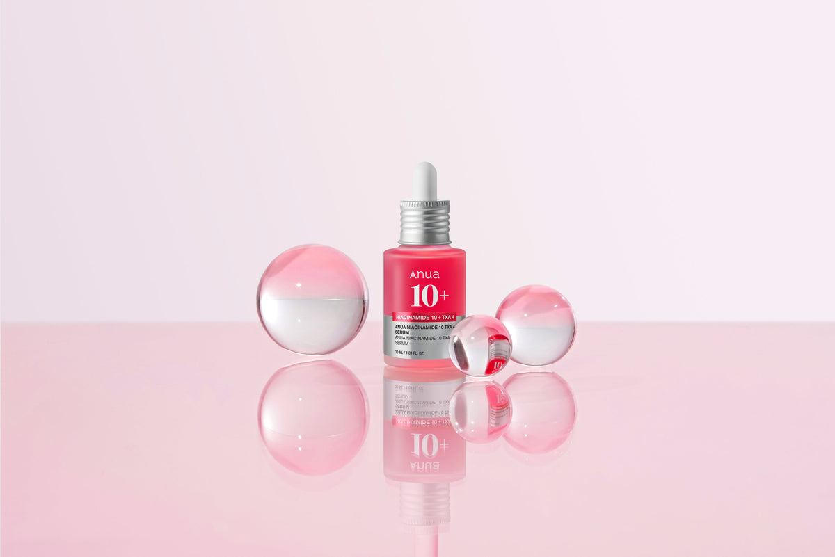 Flacon de sérum rose entouré de sphères transparentes