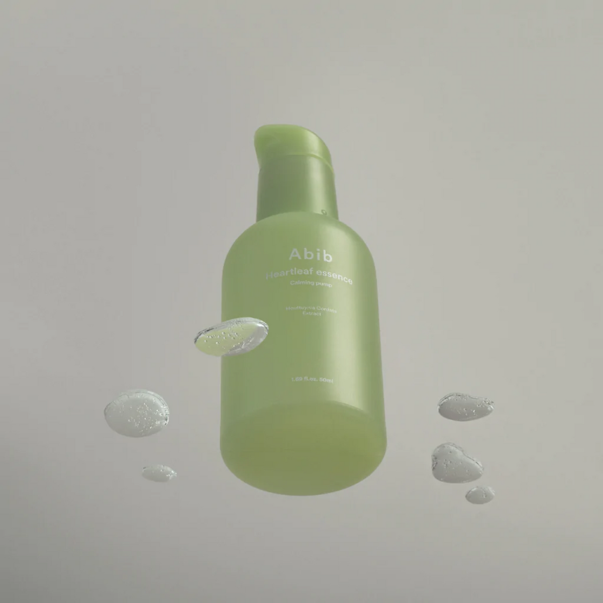 Flacon-pompe vert entouré de gouttes de gel transparent