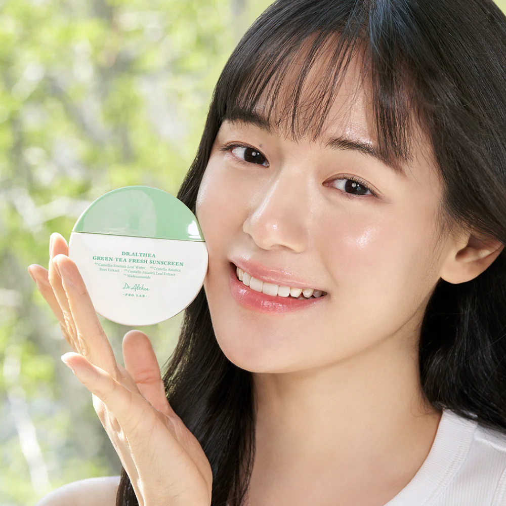 Boîtier vert et blanc de crème solaire tenu près du visage