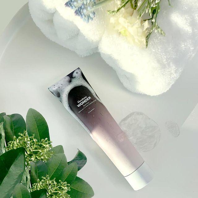 Tube de nettoyant entouré de mousse près de serviettes et de fleurs