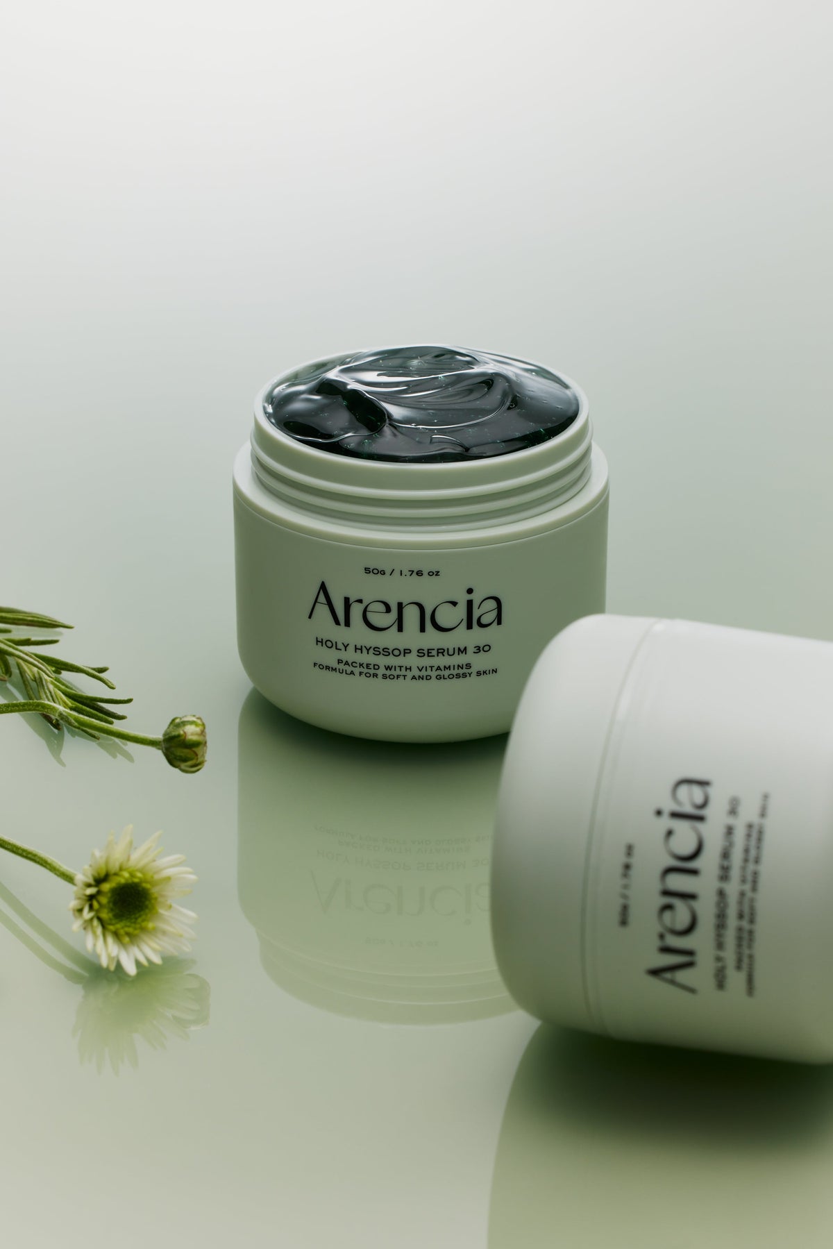 Pot de sérum ouvert sur un gel vert foncé, près de fleurs