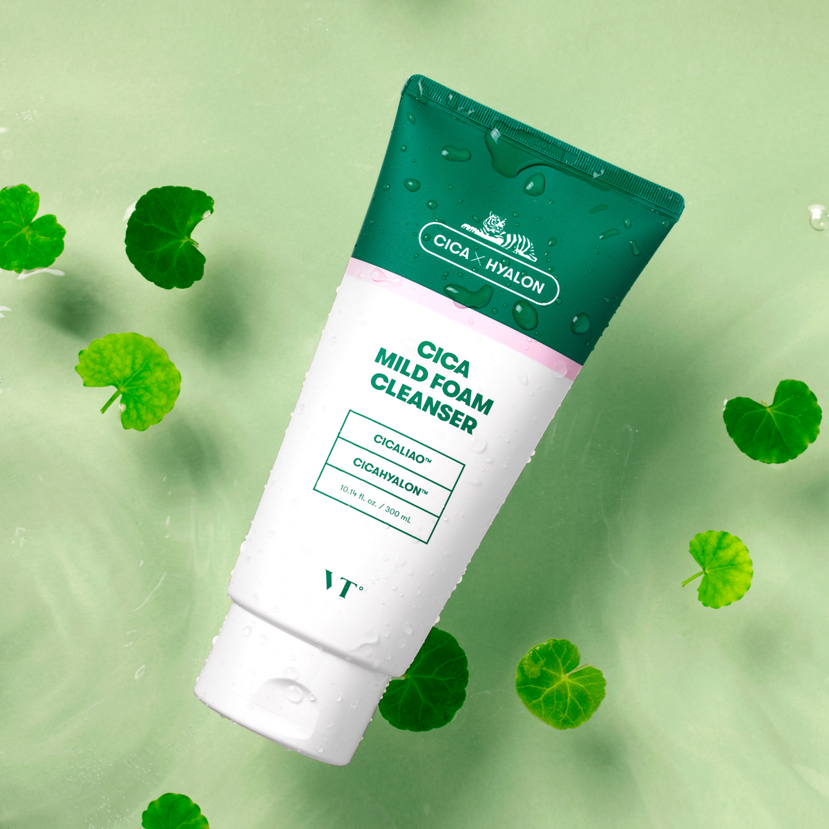 Tube de nettoyant vert et blanc entouré de feuilles de centella et de gouttes d&