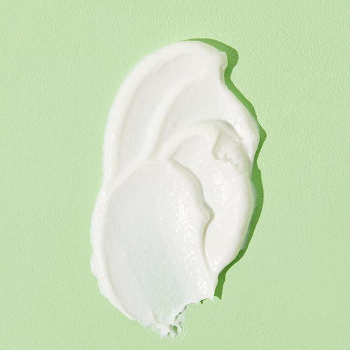 Trace de crème blanche épaisse étalée sur fond vert