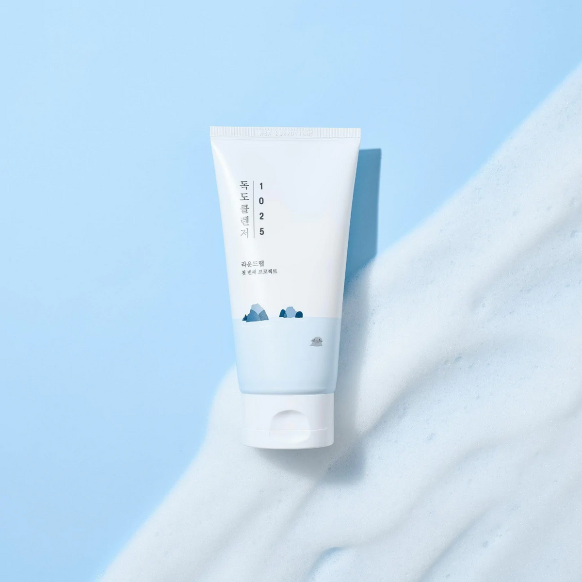 Tube de nettoyant blanc et bleu sur de la mousse