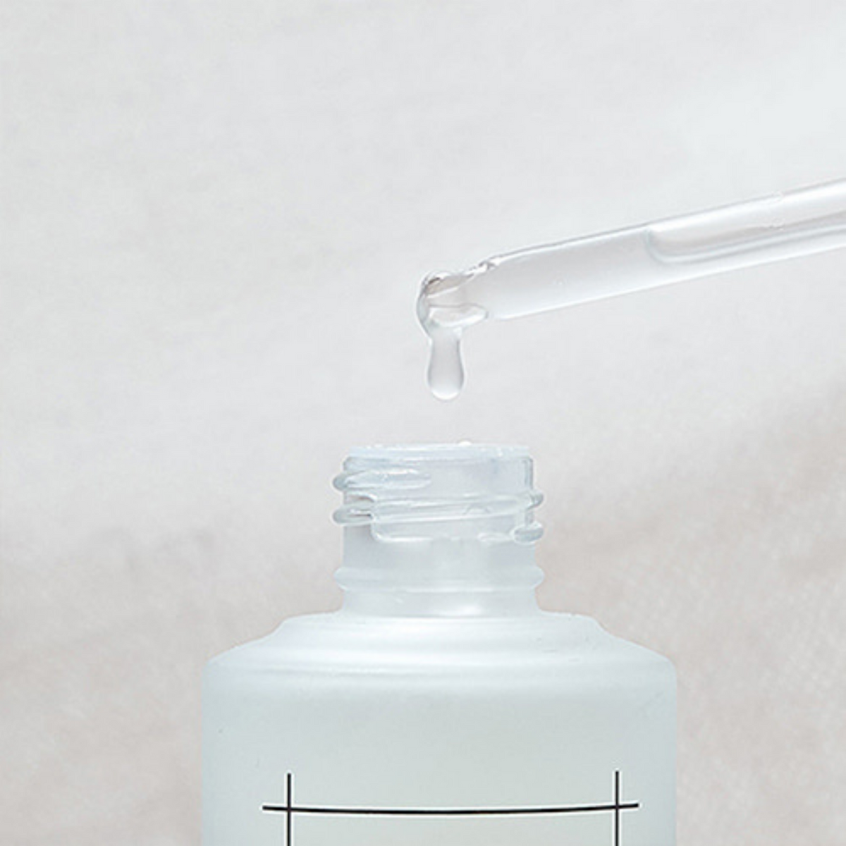 Goutte de sérum laiteux au bout de la pipette au-dessus du flacon