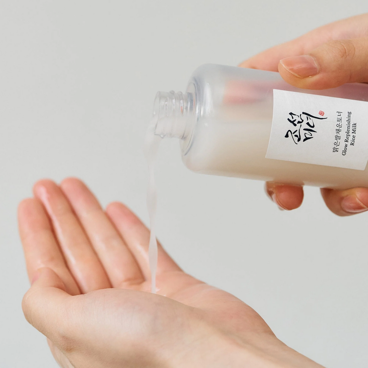 Lotion laiteuse versée dans la paume depuis le flacon