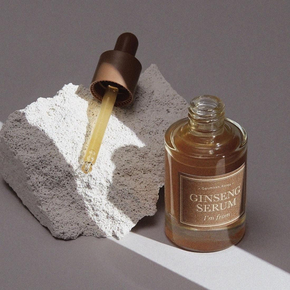 Flacon de sérum ouvert près de sa pipette posée sur une pierre