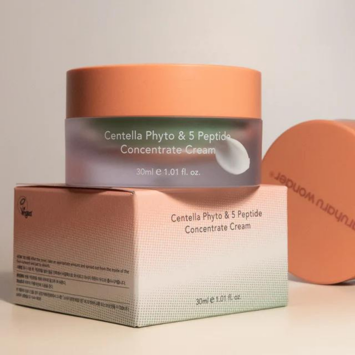 Pot de crème à couvercle orange posé sur sa boîte