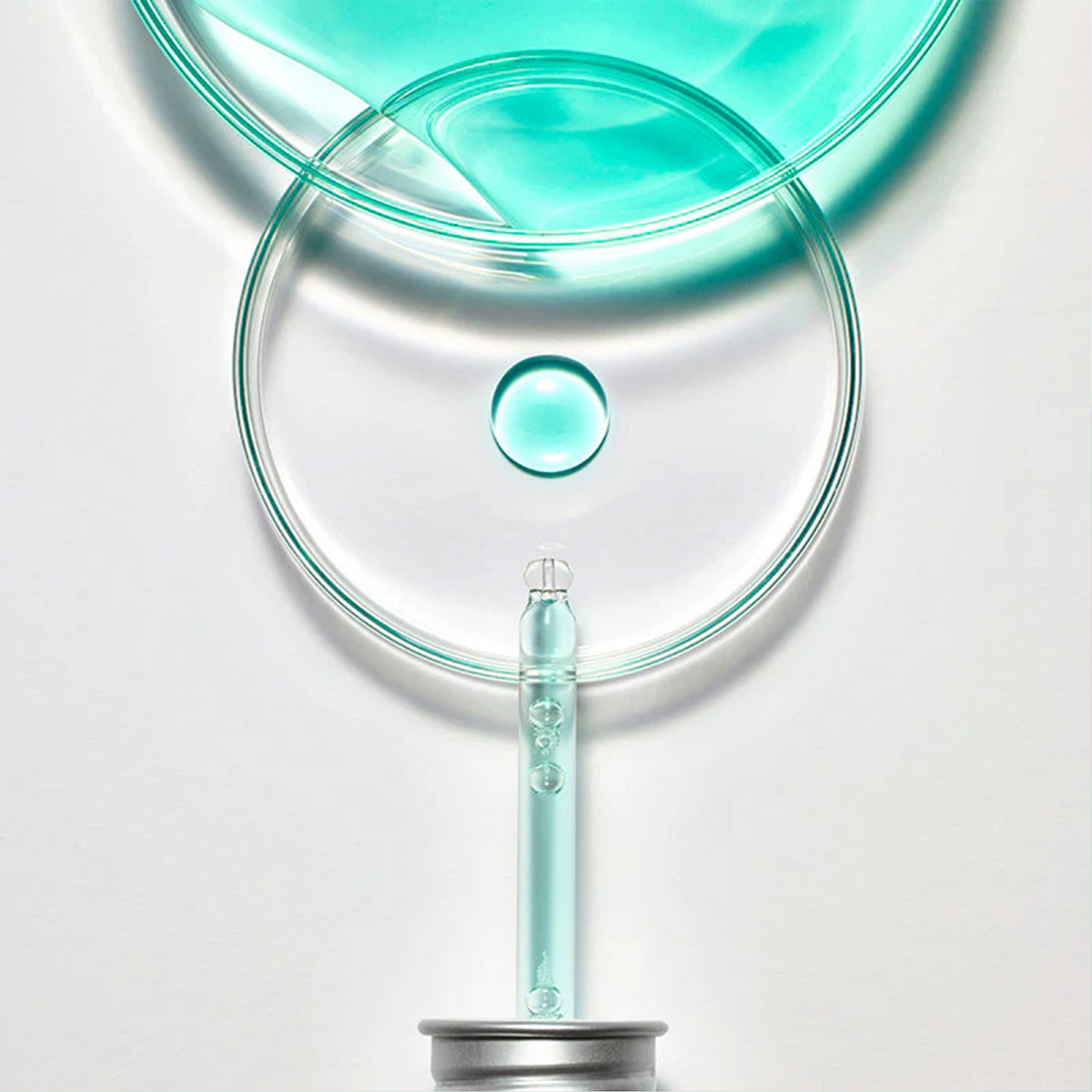 Pipette déposant une goutte de sérum dans une coupelle transparente