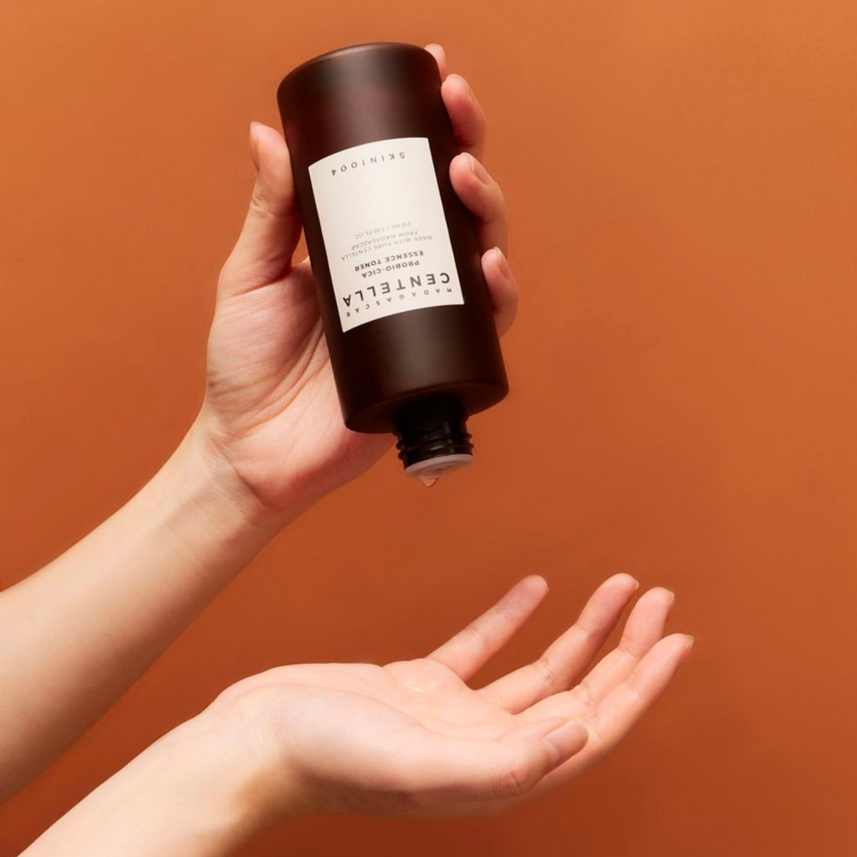 Flacon brun de lotion incliné au-dessus de la paume