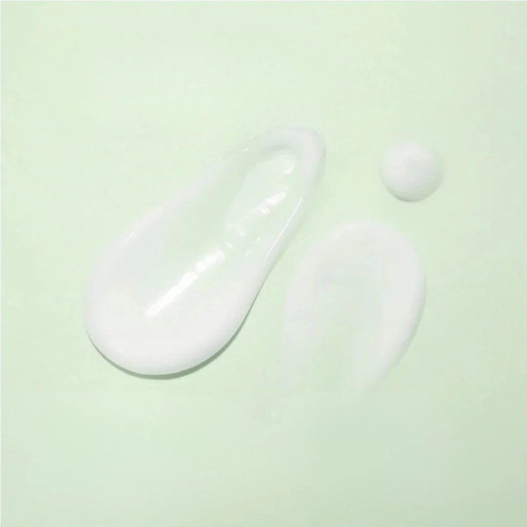 Gouttes de crème solaire blanche étalées sur fond vert