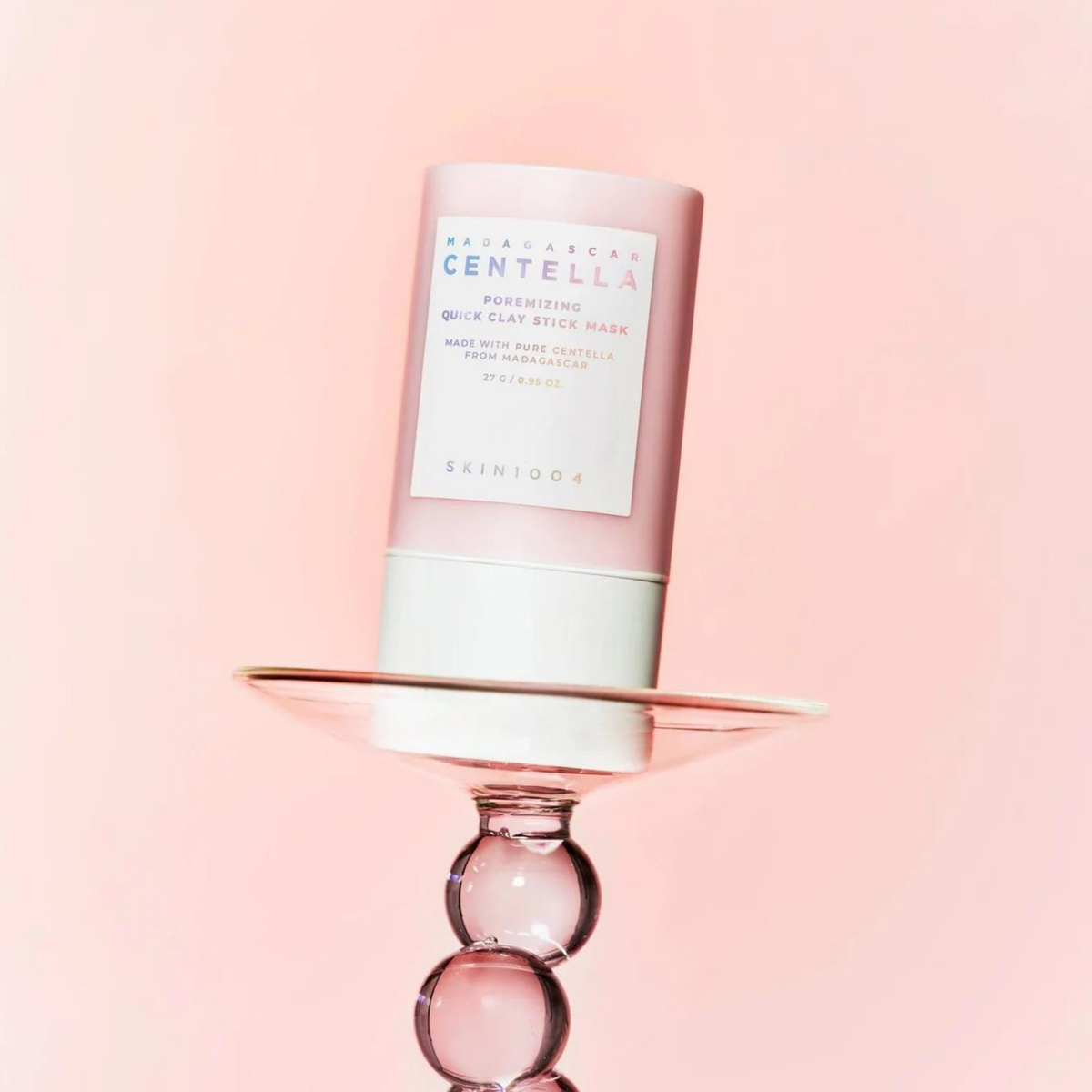 Stick de masque rose posé sur une coupe en verre