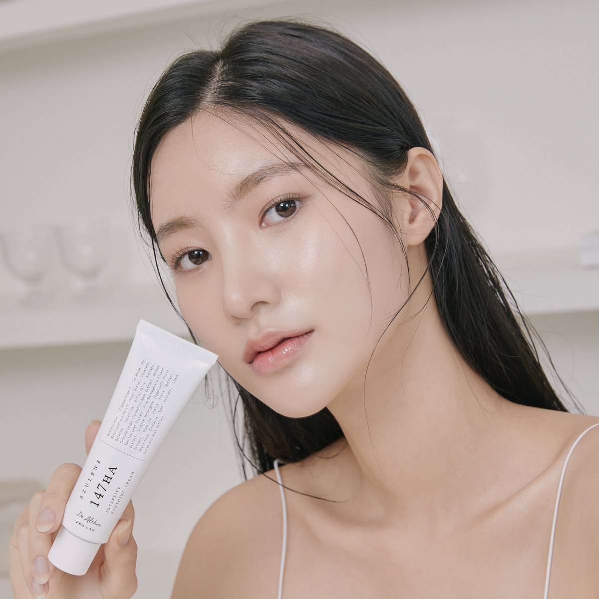 Tube de crème tenu près du visage