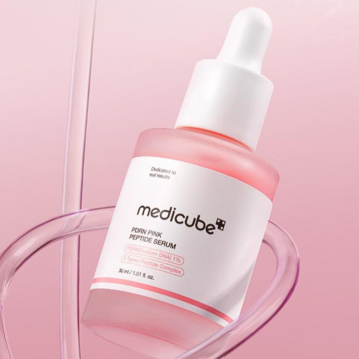 Flacon de sérum rose au milieu de tubes transparents