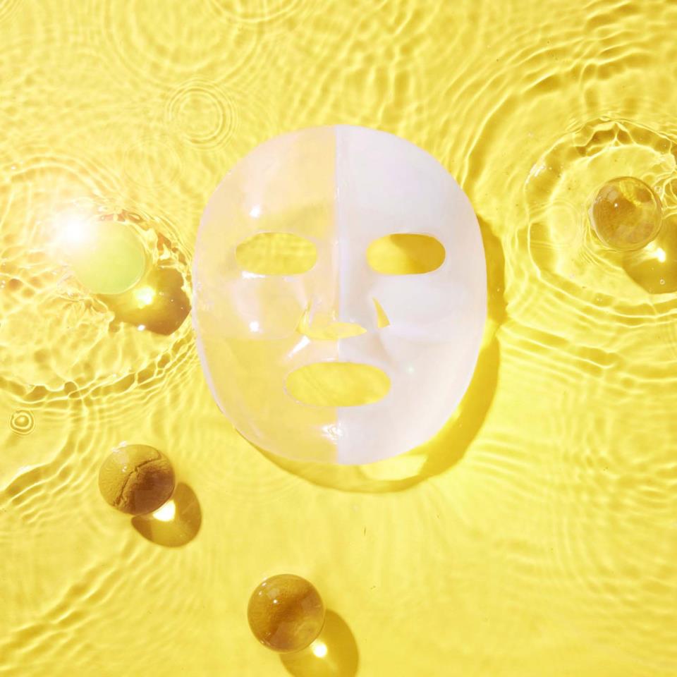 Masque hydrogel déplié sur un fond jaune entouré de sphères