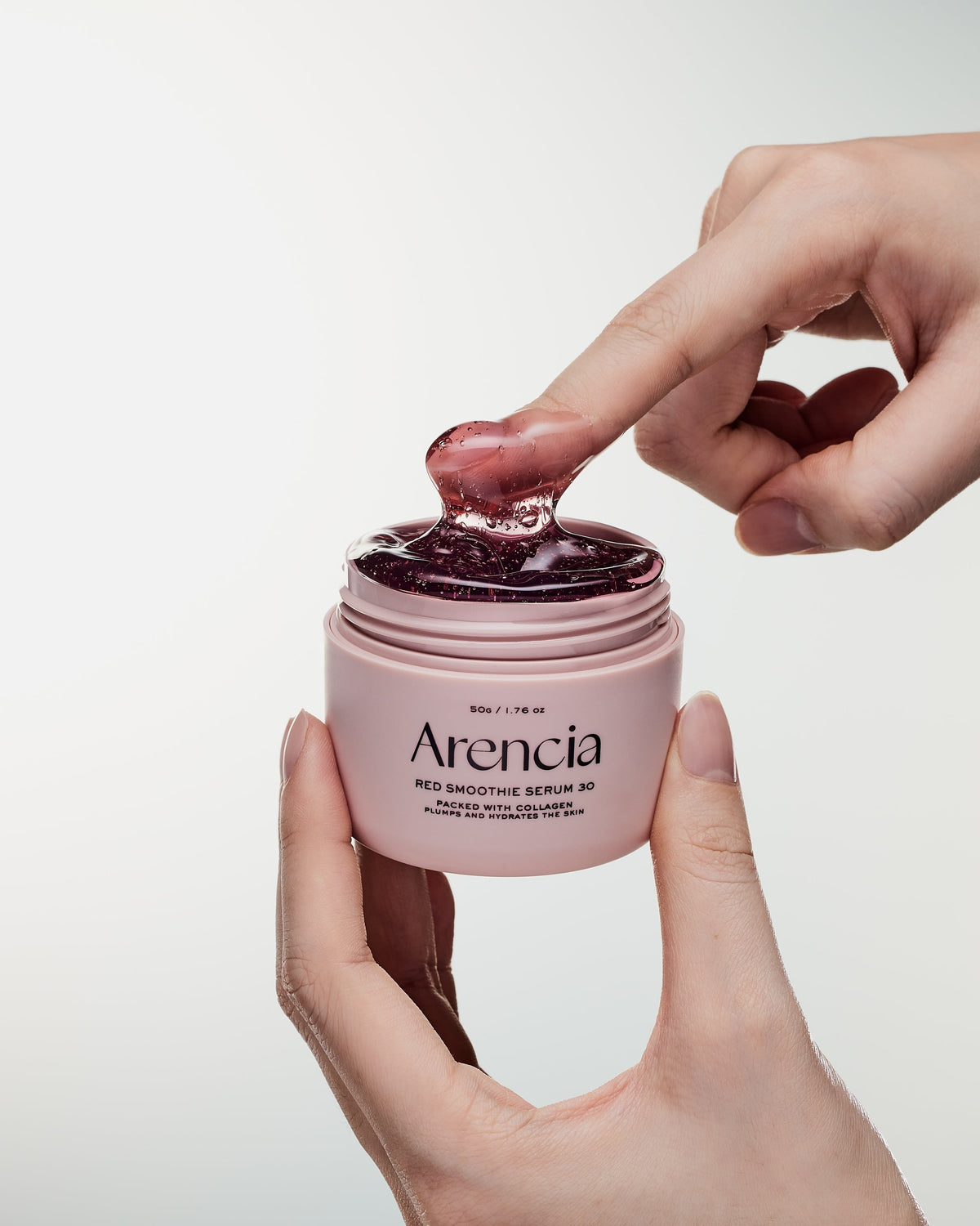 Texture gélifiée rouge étirée entre le doigt et le pot