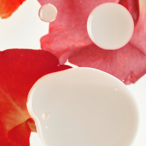 Gouttes de sérum blanc près de pétales de rose