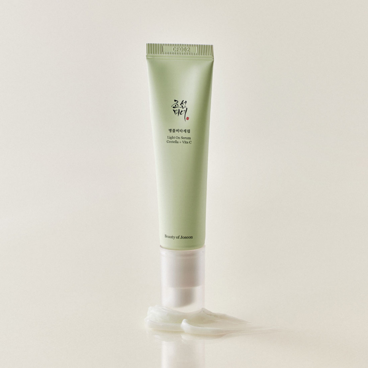 Tube-pompe vert de sérum posé sur une trace de soin blanc