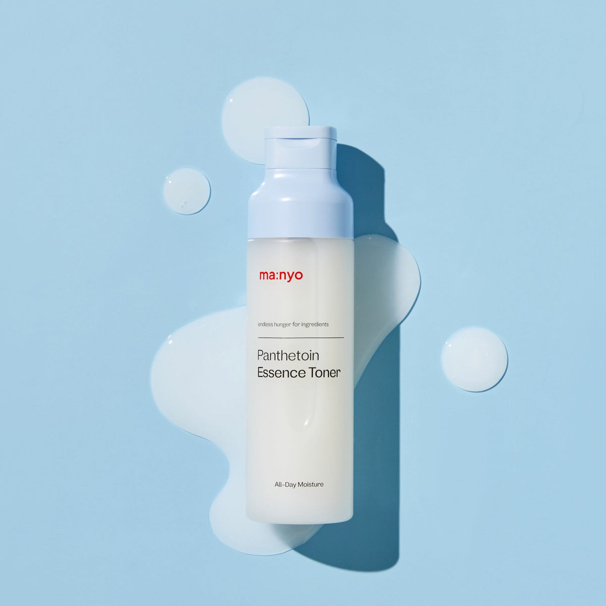 Flacon de lotion sur des gouttes laiteuses et un fond bleu