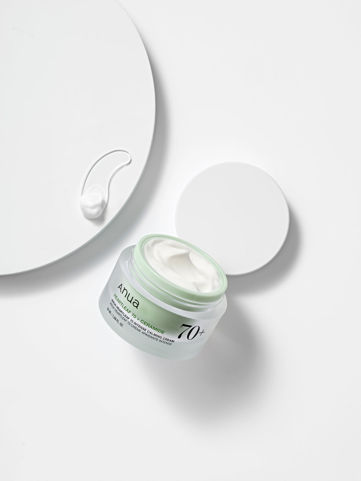 Pot ouvert et trace de crème blanche à côté du couvercle