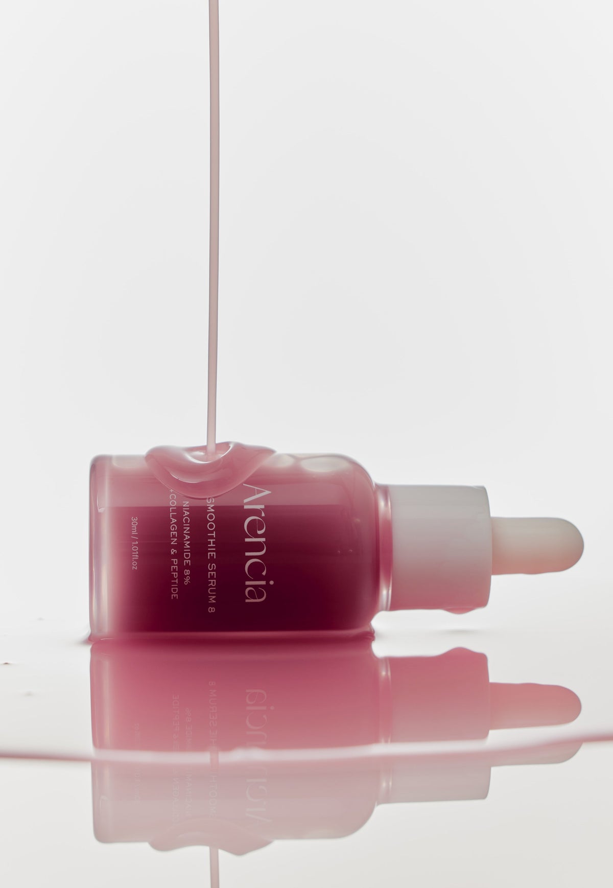 Sérum rose coulant sur un flacon couché