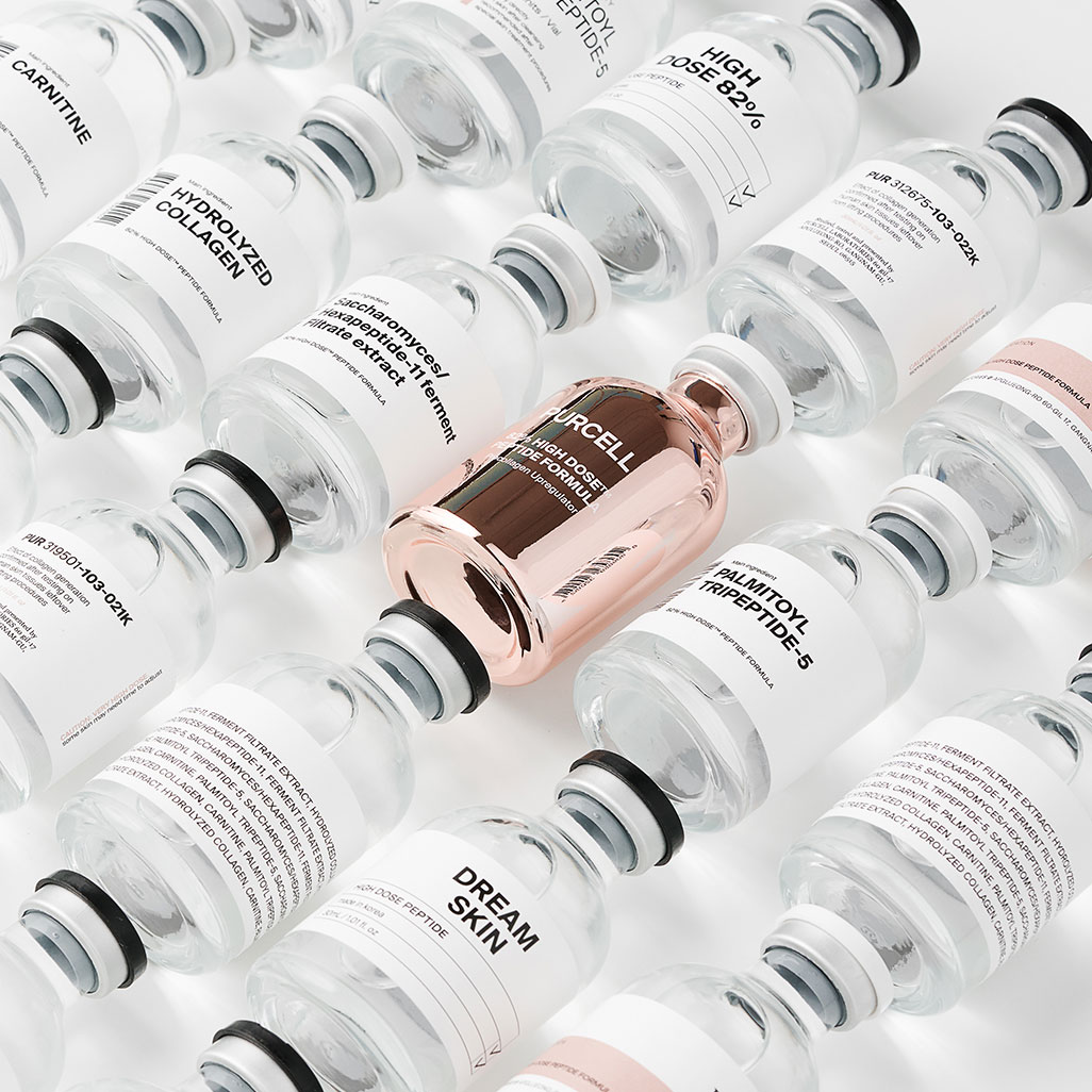 Flacon de sérum rose métallisé parmi des flacons d&