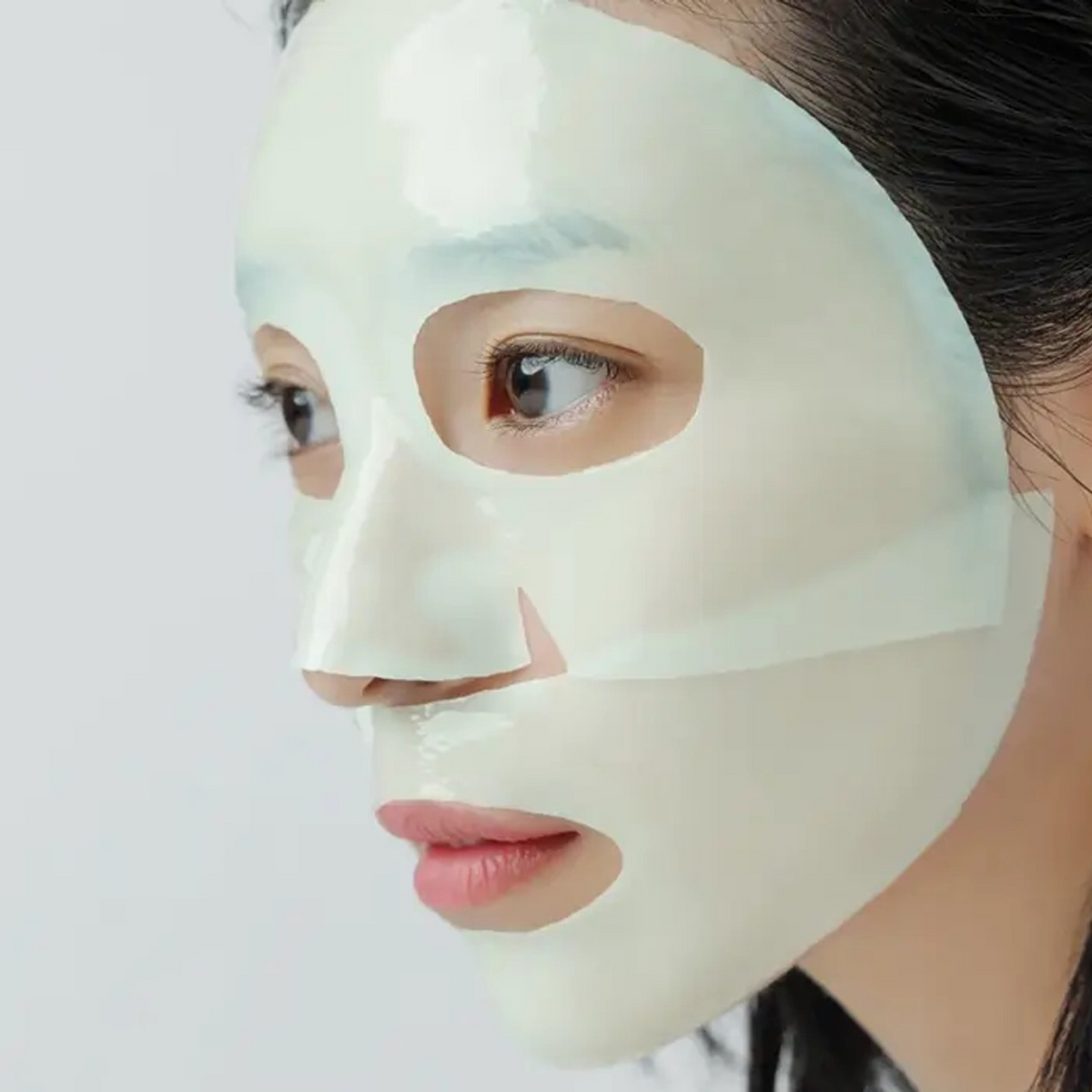 Masque hydrogel vert pâle en deux parties posé sur le visage