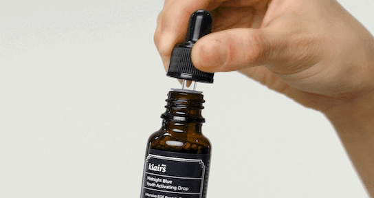Pipette retirée du flacon de sérum tenu en main