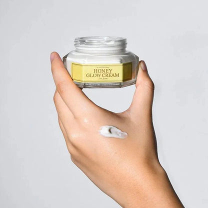 Pot de crème ouvert tenu en main avec une trace de soin sur la peau