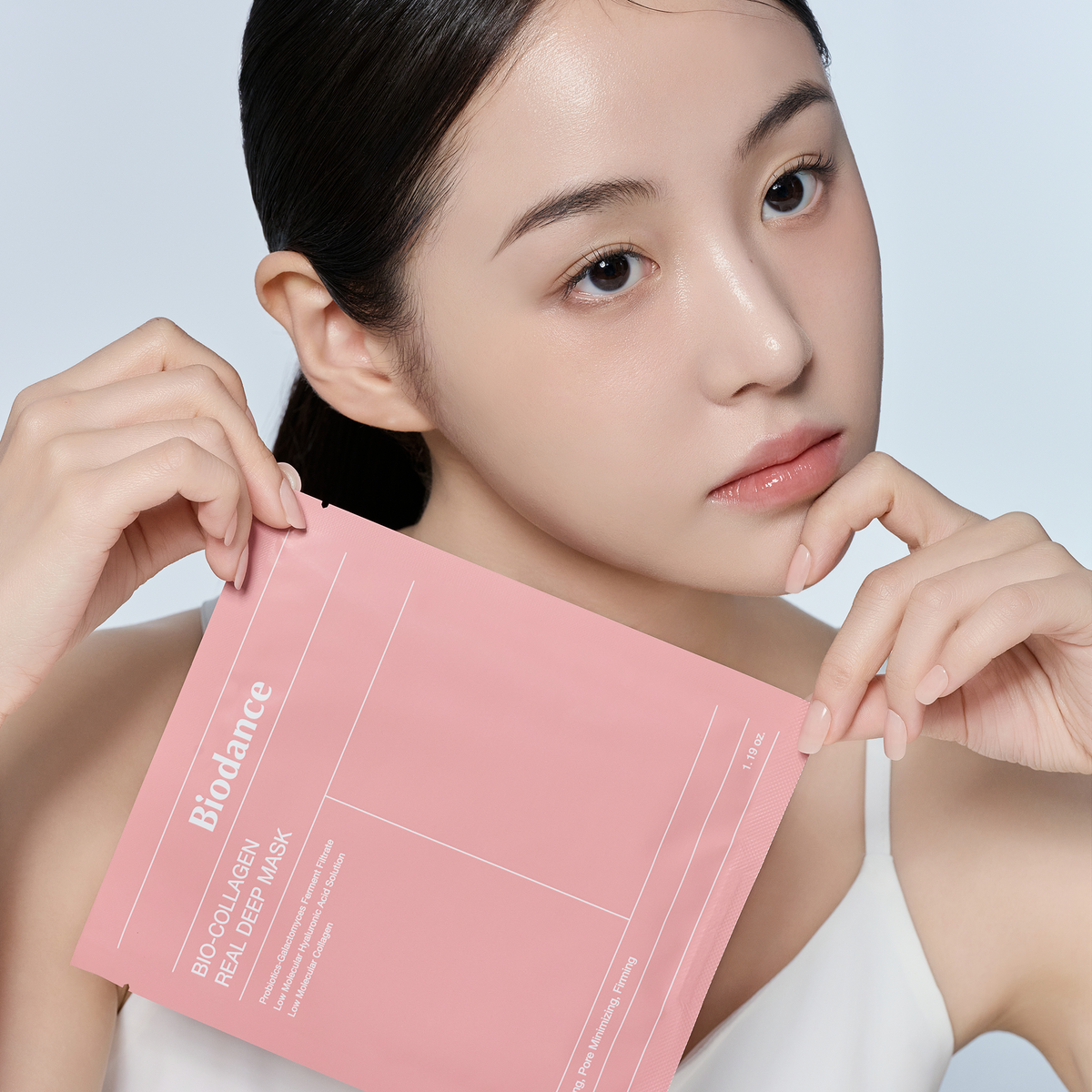 Sachet rose de masque tenu près du visage