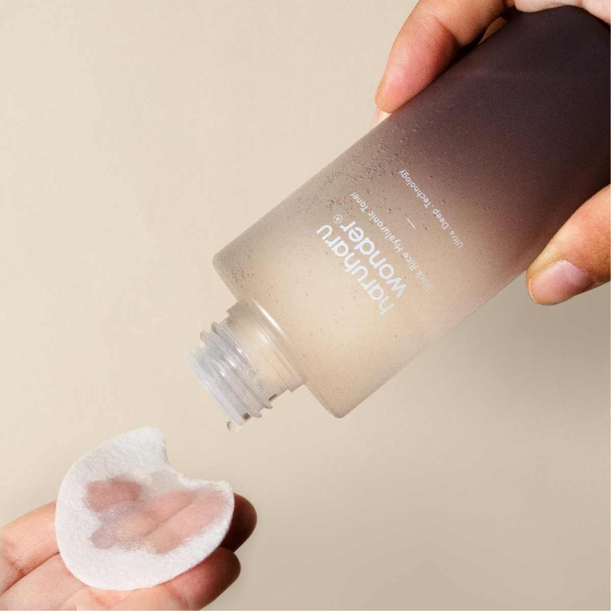 Lotion versée sur un disque de coton tenu en main