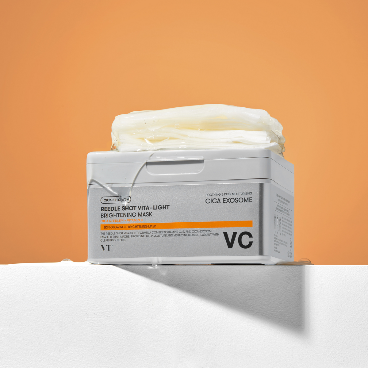 Boîte argentée et orange avec une pile de masques en tissu sur le dessus