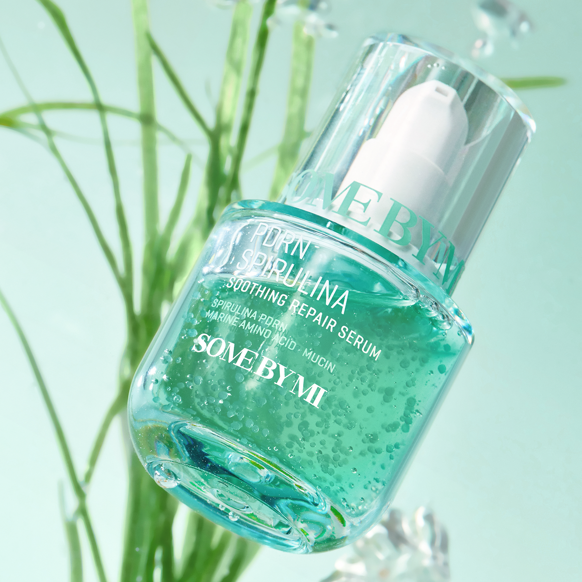 Flacon-pompe transparent contenant un sérum vert avec de petites particules