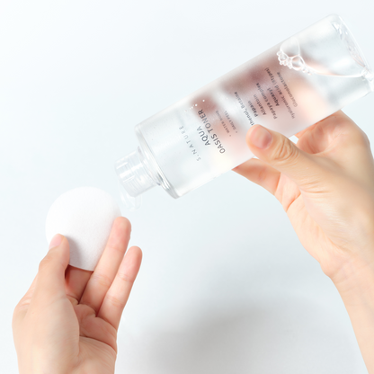 Lotion versée sur un coton rond tenu en main