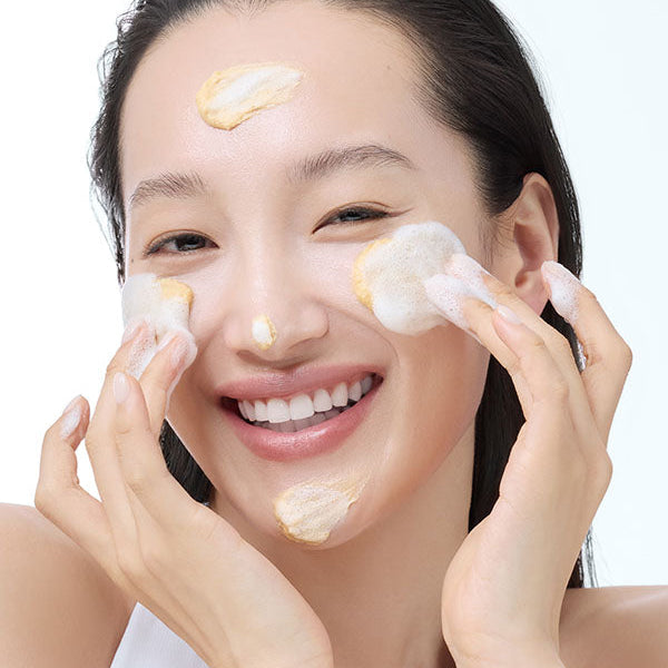 Nettoyant doré massé sur le visage et transformé en mousse
