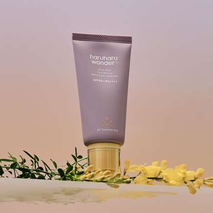 Tube mauve de solaire à bouchon jaune près de fleurs jaunes