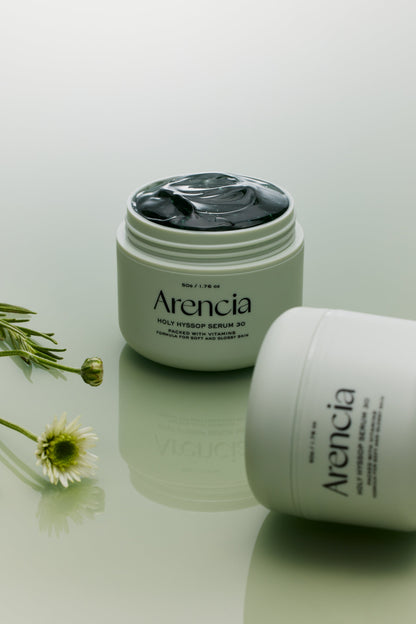 Pot de sérum ouvert sur un gel vert foncé, près de fleurs