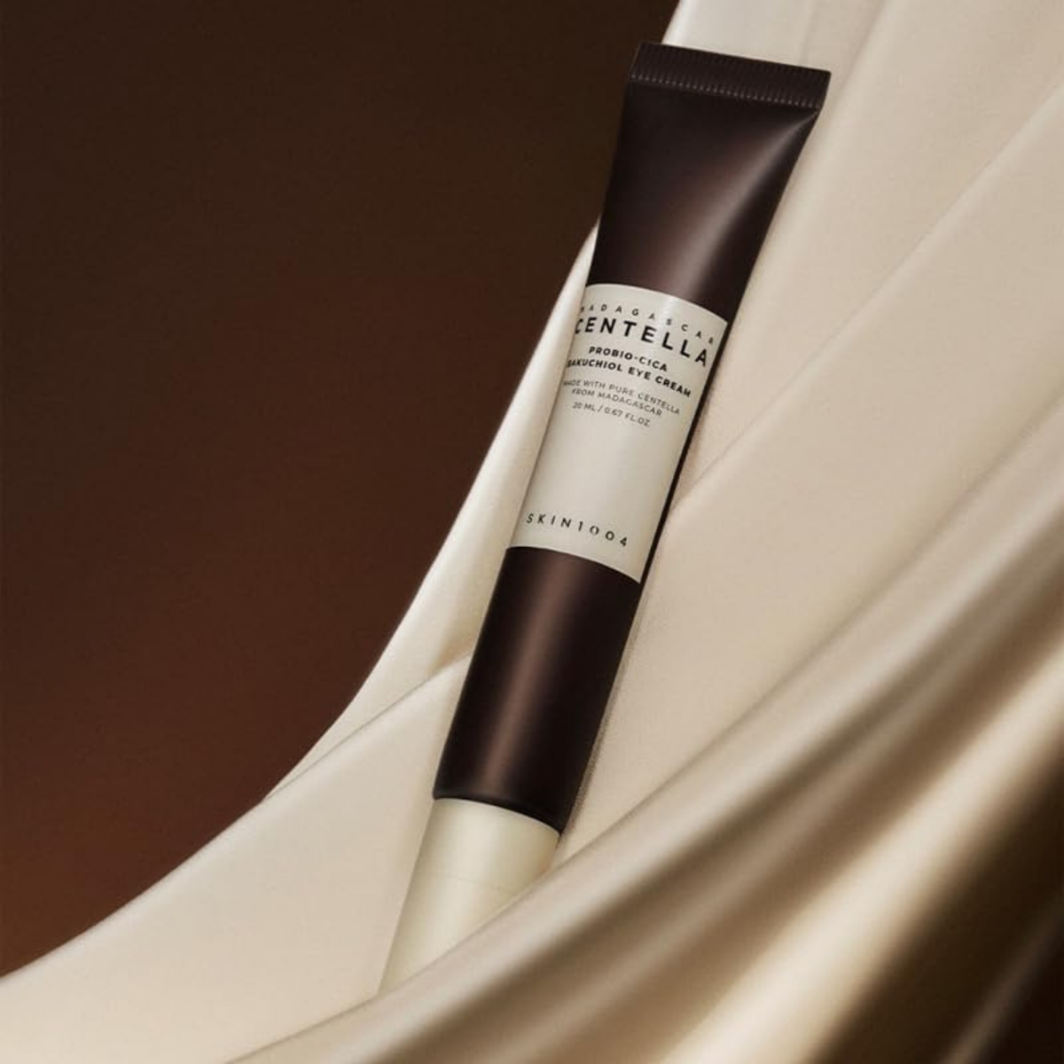 Tube brun de contour des yeux posé sur un tissu satiné beige