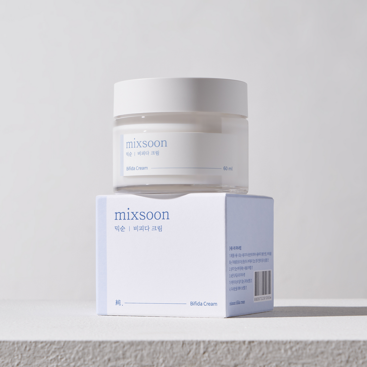 Pot de crème à étiquette bleue posé sur sa boîte