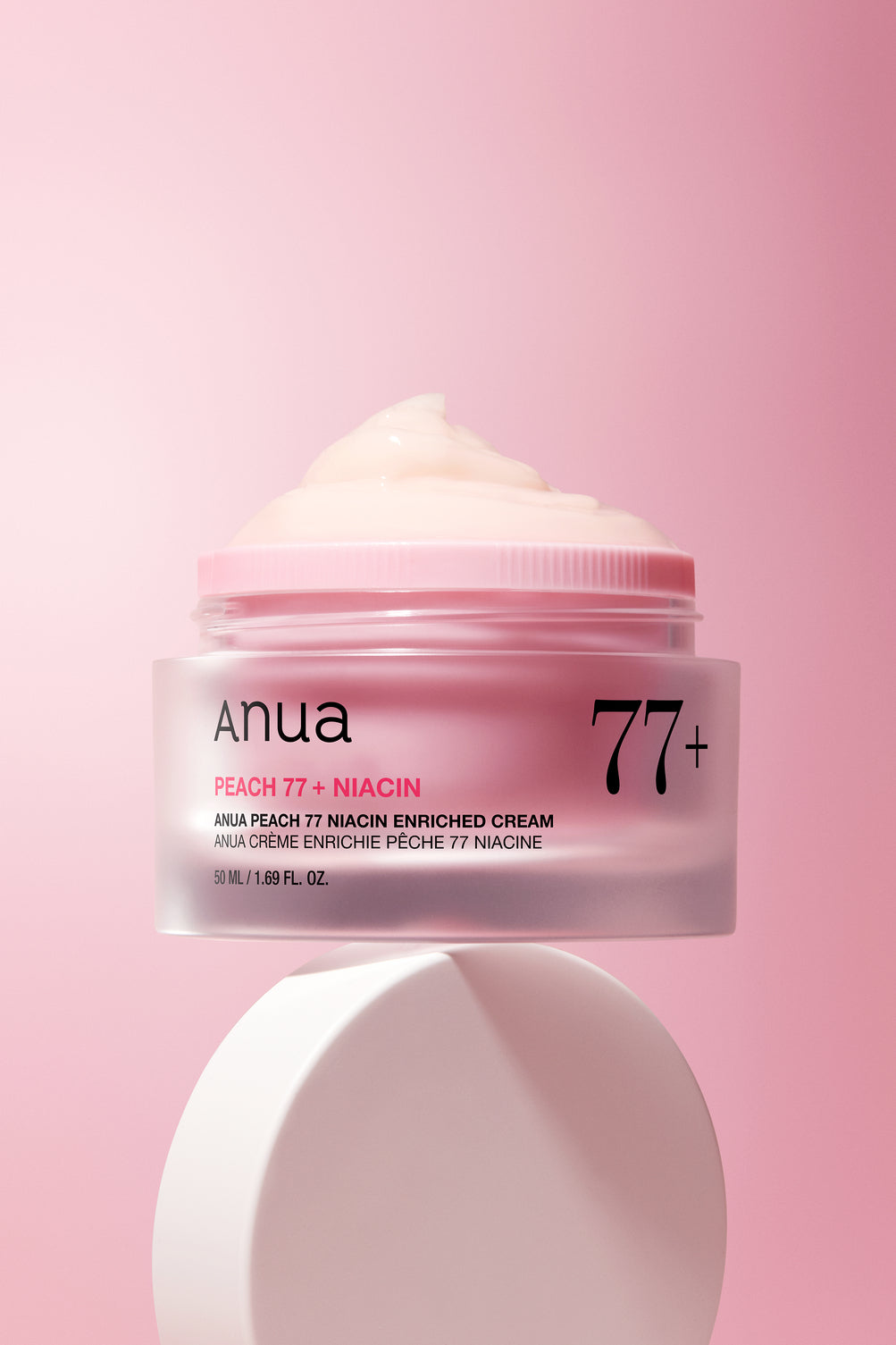 Pot rose ouvert sur une crème onctueuse, avec son couvercle en dessous