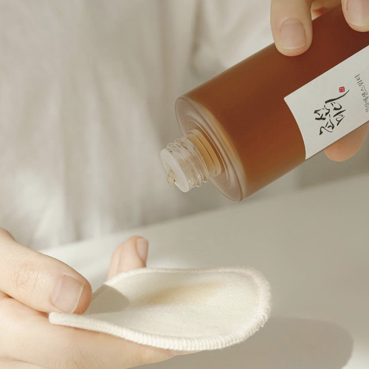 Lotion versée sur un disque de coton tenu dans la main