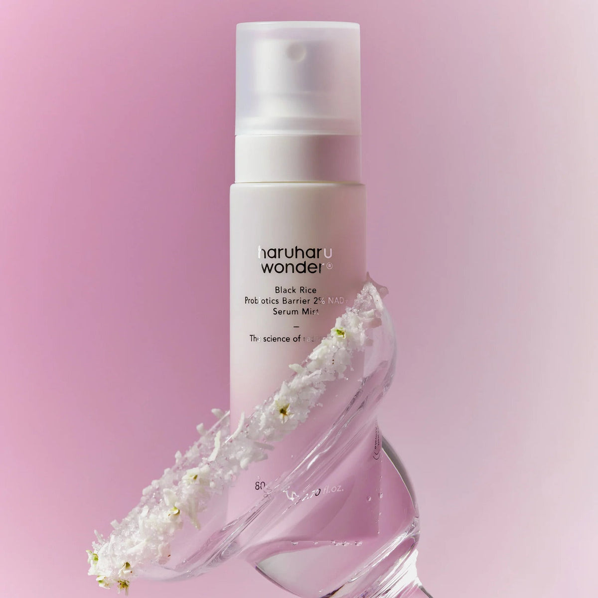 Brume-sérum sur une coupe de verre décorée de fleurs blanches