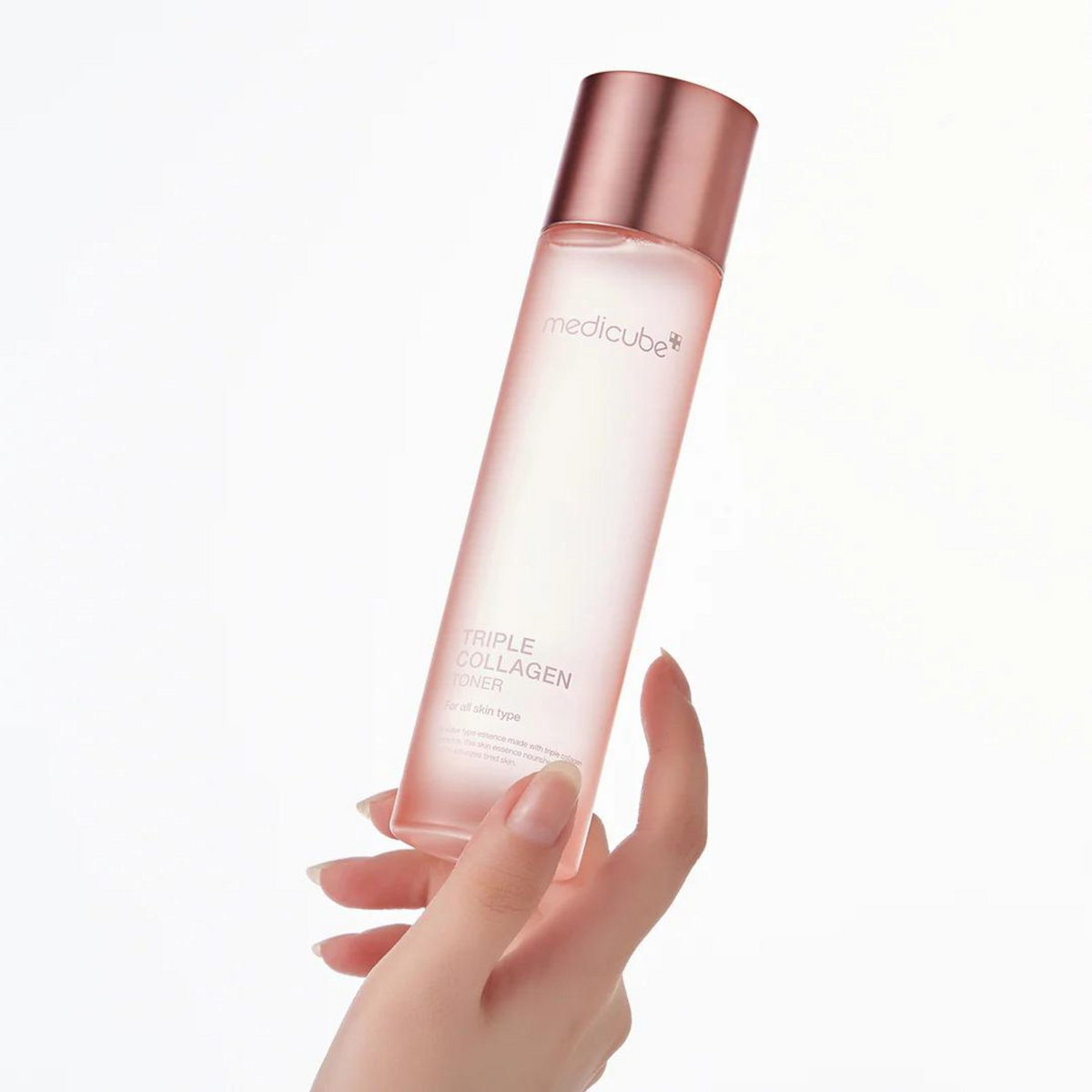 Flacon rose pâle de lotion tenu du bout des doigts