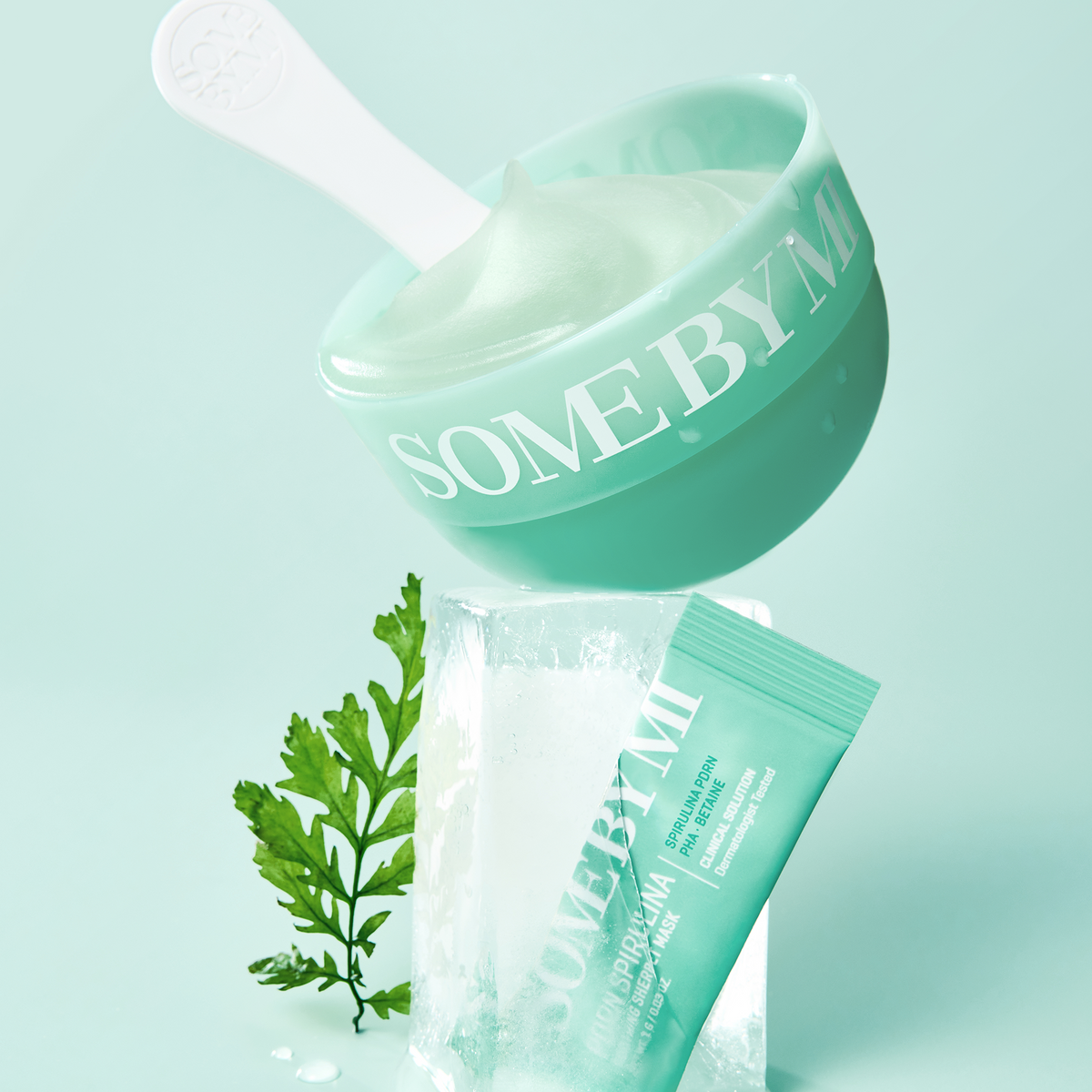 Masque vert dans un bol avec spatule, sachet, glace et algue