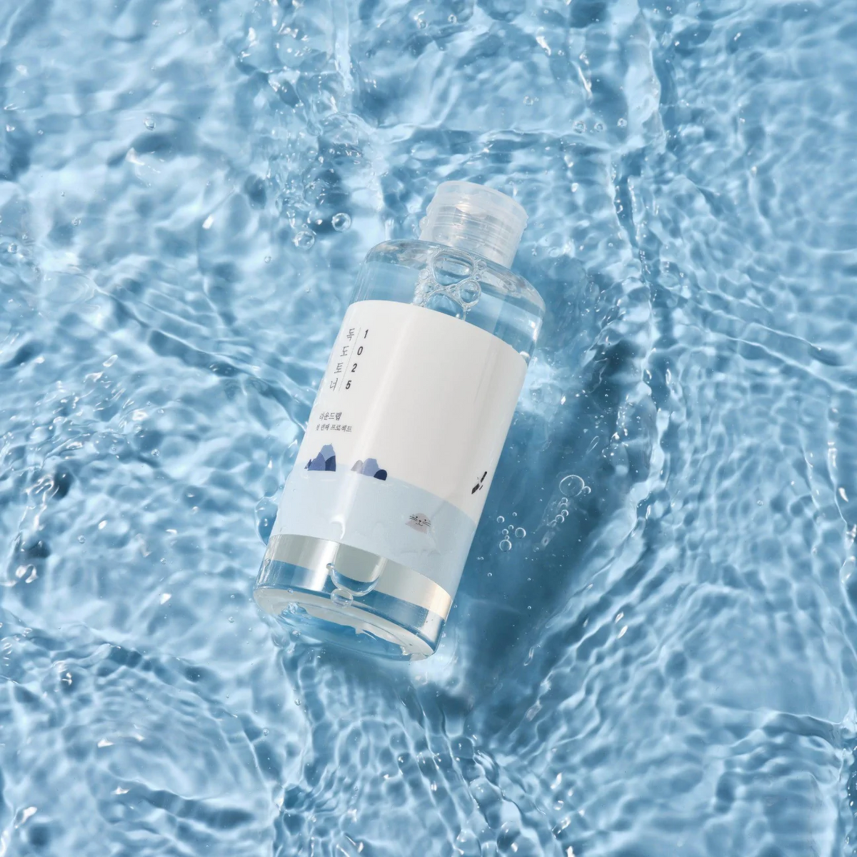 Flacon de lotion transparent posé sur de l&