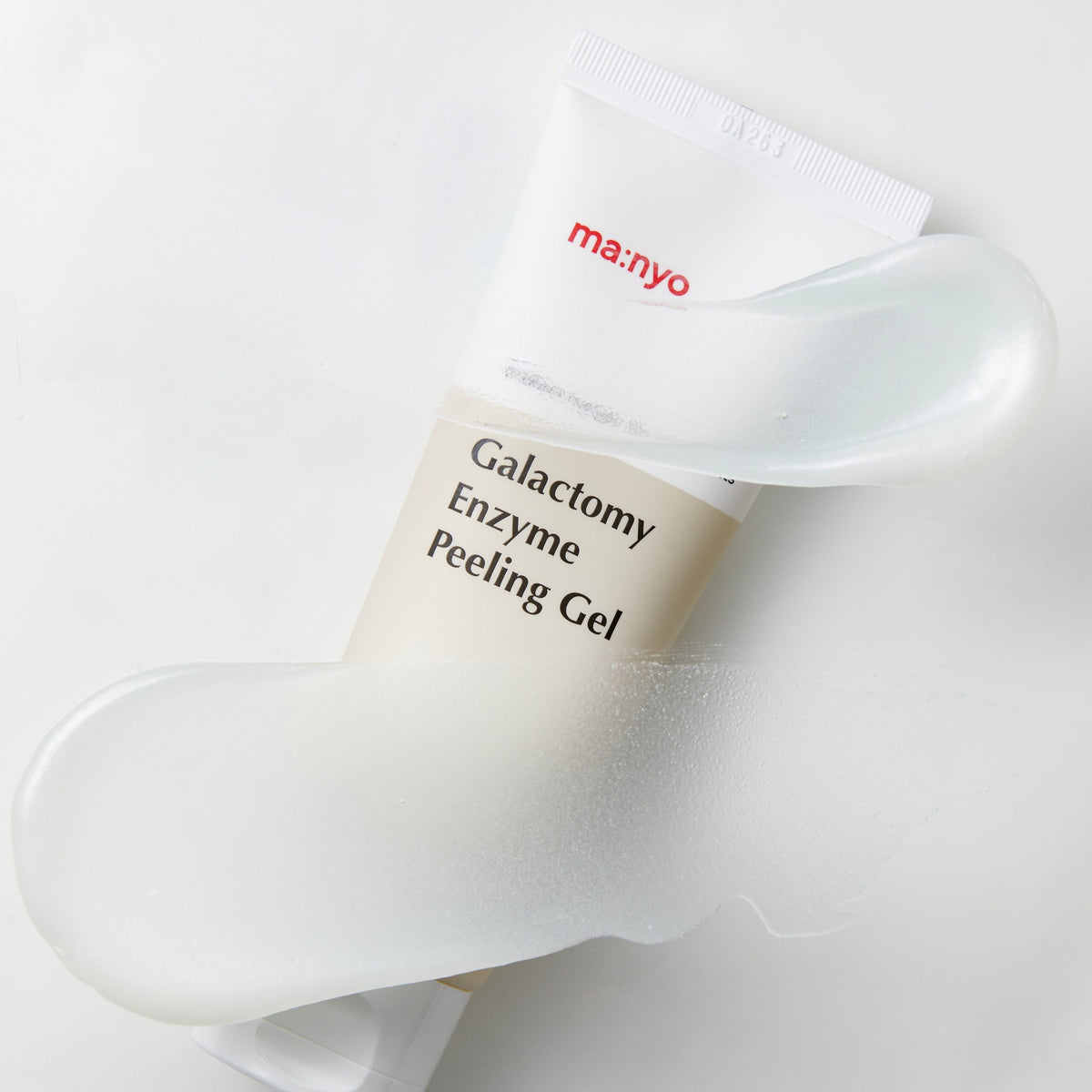 Tube de gel exfoliant entouré de traces nacrées
