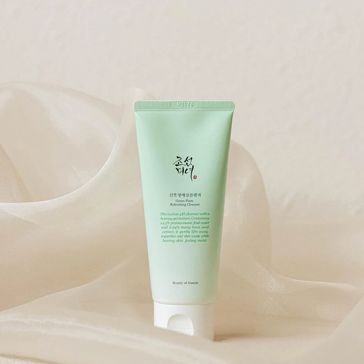 Tube vert pâle de nettoyant présenté sur un tissu clair