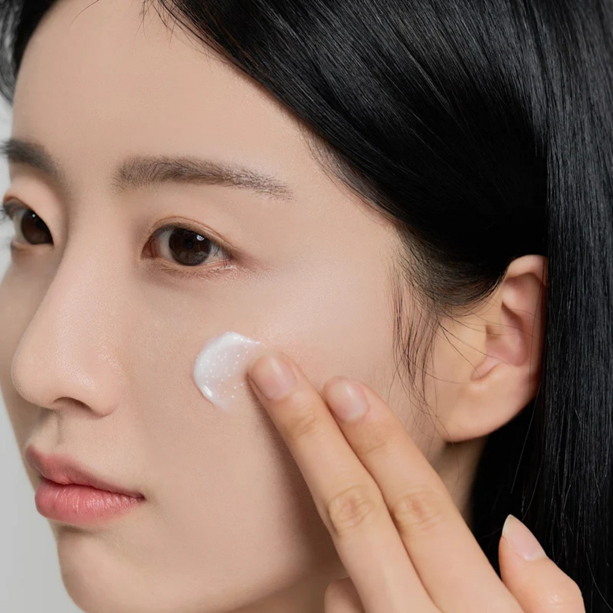 Crème à petites capsules blanches étalée sur la joue